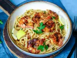 Ein Teller mit köstlichen Spaghetti mit Garnelen, garniert mit frischer Petersilie und Zitronenspalten.