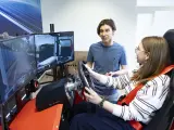 Studentka na symulatorze ciężarówki, ucząc się **studiów logistycznych**. Mężczyzna instruuje ją, jak prowadzić.