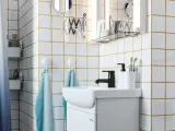 Salle de bain moderne avec carrelage blanc joint gris, lavabo, robinetterie noire et accessoires pratiques.