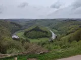 Malowniczy zakole rzeki w zielonych Ardenach, otoczone wzgórzami porośniętymi lasem.