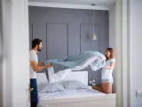 Coppia felice che cambia le lenzuola, un gesto che ci ricorda ogni quanto cambiare le lenzuola per un sonno più sano.