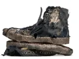 Un par de zapatillas gastadas, rotas y sucias, apiladas una sobre otra. Parecen haber vivido muchas aventuras.