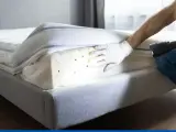Persona con guantes revisa un colchón con linterna, detectando chinches. Esencial para el control de plagas de chinches y un hogar saludable.