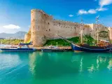 Zamek Kyrenia na Cyprze Północnym z łodziami przycumowanymi w turkusowej zatoce.