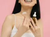 Uśmiechnięta kobieta z aparatem ortodontycznym trzyma jadeitowy roller i serum. Rozpoczyna wprowadzanie retinolu do swojej rutyny pielęgnacyjnej.