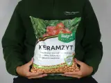 Osoba trzyma worek z napisem "Keramzyt", który jest doskonałym materiałem drenażowym i ściółkującym.