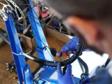 Ręce w niebieskich rękawiczkach dokonują centrowania koła rowerowego za pomocą klucza.