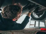 Mężczyzna naprawia podwozie Opla p1700. Widać jego rękę w rękawicy, narzędzia i puszkę WD-40.