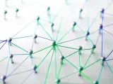Netzwerk aus silbernen Pins und bunten Fäden auf weißem Untergrund.
