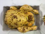 Un pollo al ast, sazonado y listo para hornear, recibe un chorrito de aceite para una cocción perfecta.