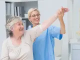 Pielęgniarka pomaga starszej pacjentce w ćwiczeniach rehabilitacyjnych. To część kursu leczenia ran.