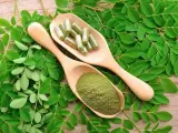 Feuilles de moringa, poudre verte et gélules sur des cuillères en bois. Découvrez les nombreux moringa bienfaits pour votre santé.