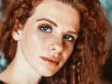 Primo piano di una ragazza con lentiggini e capelli rossi, con un trucco naturale che esalta la sua bellezza.