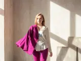 Młoda kobieta w białej koszuli i spodniach, na ramieniu zarzucony marynarka w intensywnym, **magenta kolorze**.