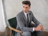 Elegancki mężczyzna w szarym garniturze i białej koszuli, zastanawia się, jaki krawat do szarego garnituru i białej koszuli będzie najlepszy.