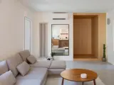 Salon épuré avec canapé modulable, table basse en bois et un coin boisé rappelant une maison style japonais en France.