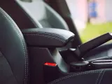 Wnętrze samochodu: czarna skórzana tapicerka, podłokietnik, hamulec ręczny i przycisk auto hold.