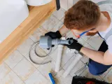 Hydraulik z narzędziem wuko naprawia odpływ pod umywalką.
