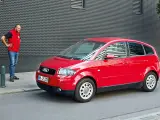 Mann steht neben rotem Audi A2, der für seine audi a2 schwachstellen bekannt ist.