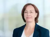 Agata Witkowska, aktorka, w granatowej marynarce i białej bluzce, uśmiecha się lekko.