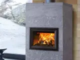 Chimenea moderna de piedra gris con fuego crepitante. Es hora de insertarleña para mantener el calor.
