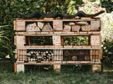 Domek dla owadów z palet, pokazujący, co można zrobić ze śmieci: drewno, szyszki i gałązki tworzą schronienie.