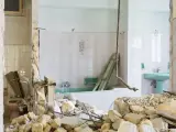 Ruiny łazienki po remoncie. Zniszczone ściany, gruz i wanna. Kara za mieszkanie w nieodebranym domu.