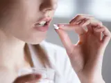 Kobieta bierze tabletkę clindamycin mip 600, trzymając szklankę wody.