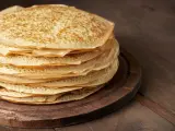 En hög med gyllene pannkakor på en träbricka. Perfekt för att frysa in och njuta av senare.