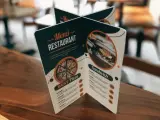 Carta de un restaurante con imágenes de pizza y sándwich. Muestra opciones de menú y precios.