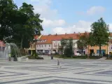 Dziecko biega po placu z fontanną, otoczonym kamienicami. To największy rynek w Polsce, tętniący życiem.