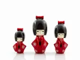 Trzy urocze lalki kokeshi w czerwonych kimonach z białymi wzorami. Idealny pomysł, co przywieźć z Japonii jako pamiątkę.