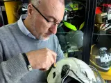 Uomo con cacciavite regola la visiera di un casco bianco, assicurandosi che il casco debba avere la visiera priva di graffi.