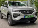 Srebrny Dacia Spring Electric z zieloną tablicą rejestracyjną WE 632YJ zaparkowany na drodze.