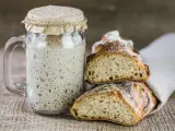 Un barattolo di rinfresco lievito madre accanto a fette di pane rustico.