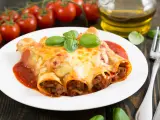 Cannelloni kontra naleśniki z mięsem: zapieczone w sosie pomidorowym i serze, ozdobione bazylią. Obok pomidorki i oliwa.
