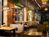 Un restaurante moderno con ladrillo visto, plantas colgantes y columpios. Un lugar acogedor que inspira lo que se necesita para abrir un restaurante.