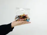 En hand håller en presentkorg i cellofan fylld med choklad.
