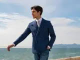 Uomo con abito doppiopetto blu a righe, camicia bianca e cravatta, jeans. Un look smart elegant dress code uomo con vista mare.
