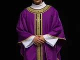 Eleganckie fioletowe szaty liturgiczne z bogatymi złotymi zdobieniami, noszone przez mężczyznę z dłońmi złożonymi na piersi.