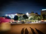 Ombre d'un mineur dehors la nuit, projetées sur une place éclairée par des bâtiments modernes.