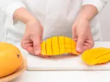Ręce kroją dojrzałe mango na kostki. Czy mango ma pestkę? Tak, ale jej nie widać, bo jest w środku.