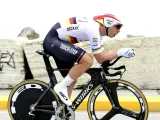 Cyclist in full aerodynamic gear, focused on time trial training, pushing hard on a specialized bike.