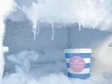 En burk jordgubbsglass står i en frys full av frosta av frys. Isformationer hänger från taket.