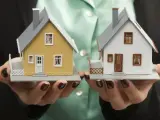 Dwie miniatury domów, żółty i biały, w dłoniach. Wybór idealnego domu wielorodzinnego.