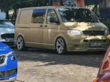 Złoty bus, przeróbka busa na kampera przepisy. Stylowe felgi, naklejki i palma na boku.
