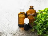 Butelki z olejkiem z oregano, pomocne w walce z grzybicą, obok świeżych gałązek tej rośliny.