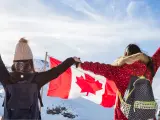 Zwei junge Frauen mit Rucksäcken und der kanadischen Flagge in den Bergen. Ein unvergesslicher Kanada Austausch!