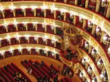 Elegancka loża w teatrze, z czerwonymi aksamitnymi siedzeniami i złotymi zdobieniami, czeka na widzów.