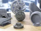 A collection of intricate 3D printing spare parts, including a lattice sphere, gears, and a vent, showcasing advanced manufacturing capabilities.